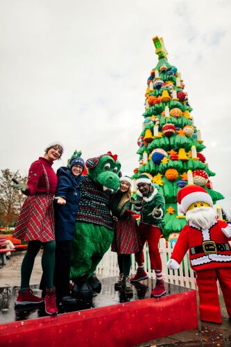 LEGOLAND Geschäftsführerin Manuela Stone mit Parkmaskottchen Drache Olli und seinen Winter-Elfen vor dem 10 Meter hohen LEGO DUPLO Baum.