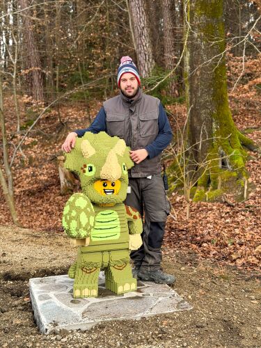 Modellbauer Marcel neben einem der neuen LEGO Modelle, die auf dem Weg vom LEGOLAND Feriendorf zum Park entdeckt werden können.