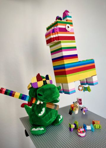Parkmaskottchen Olli freut sich über eine bunt gefüllte LEGO Piñata, eines der kreativen Modelle, das hunderte Familien anlässlich der LEGOLAND Familien-Challenge eingereicht haben.